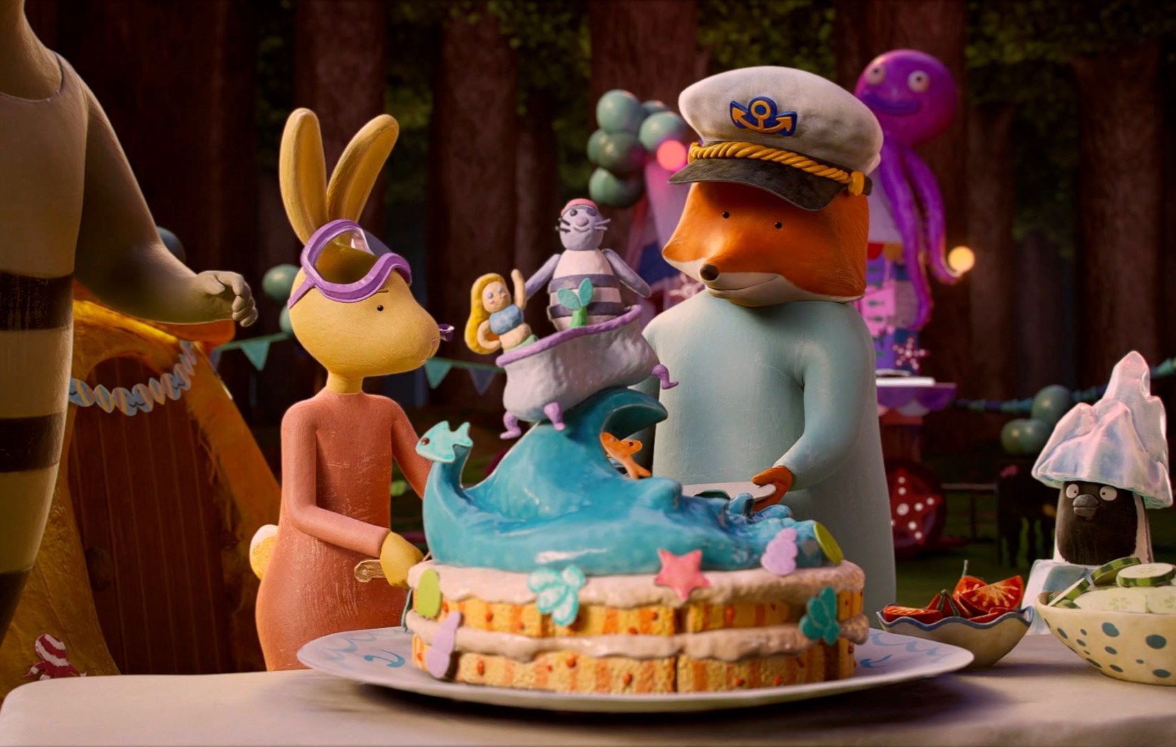 Animationsfilm: Ein Hase und ein Fuchs schneiden eine Torte an. Die Torte ist bunt mit bunten Figuren.