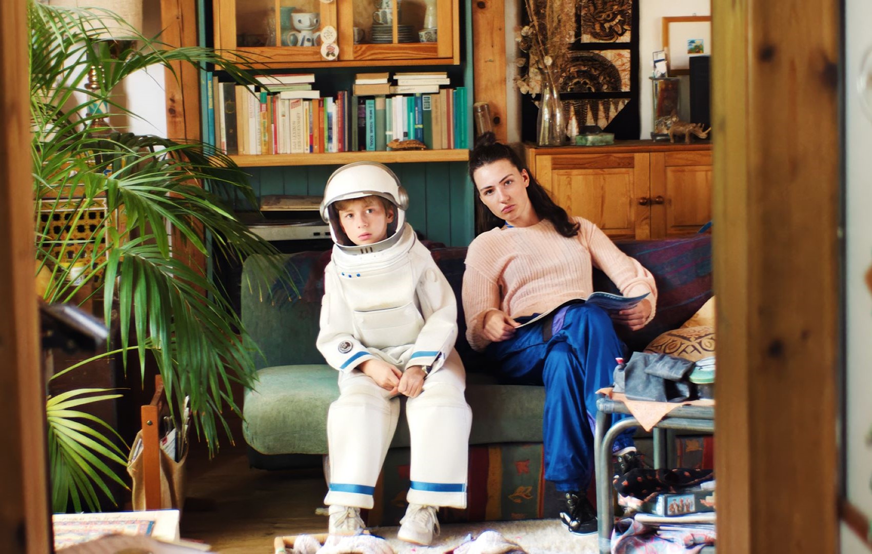 Ein Junge und ein Mädchen sitzen auf der Couch. Der Junge trägt einen Astronautenanzug.